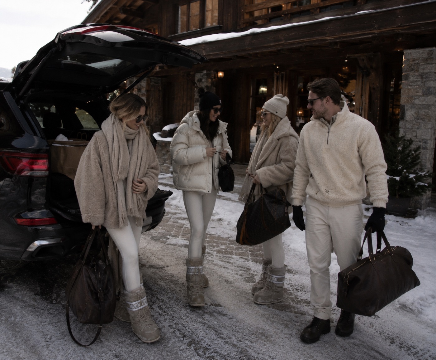 Group in cream apres-ski layers outside a snowy chalet.